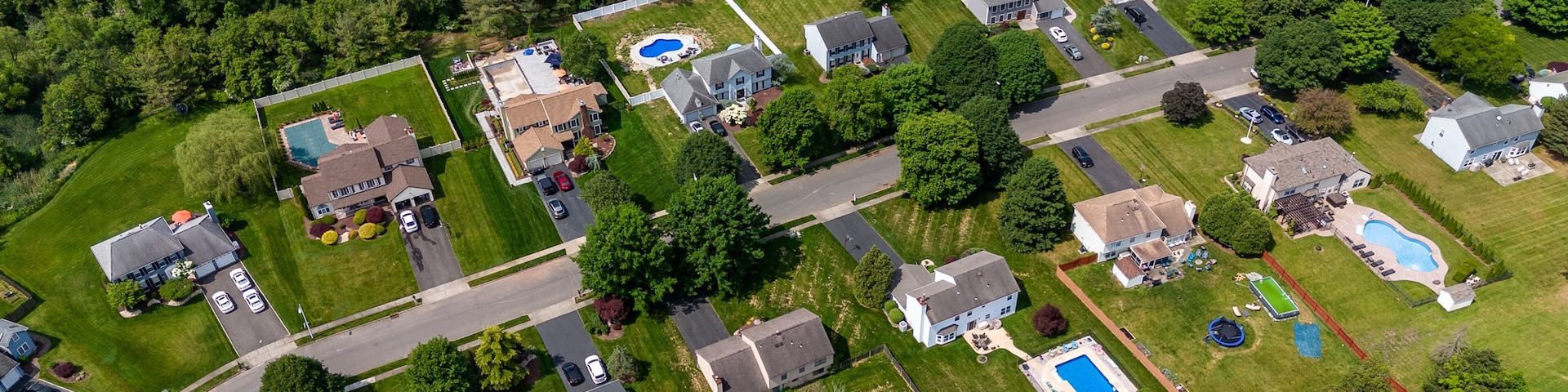 Um bairro residencial com casas, piscinas e gramados bem cuidados.