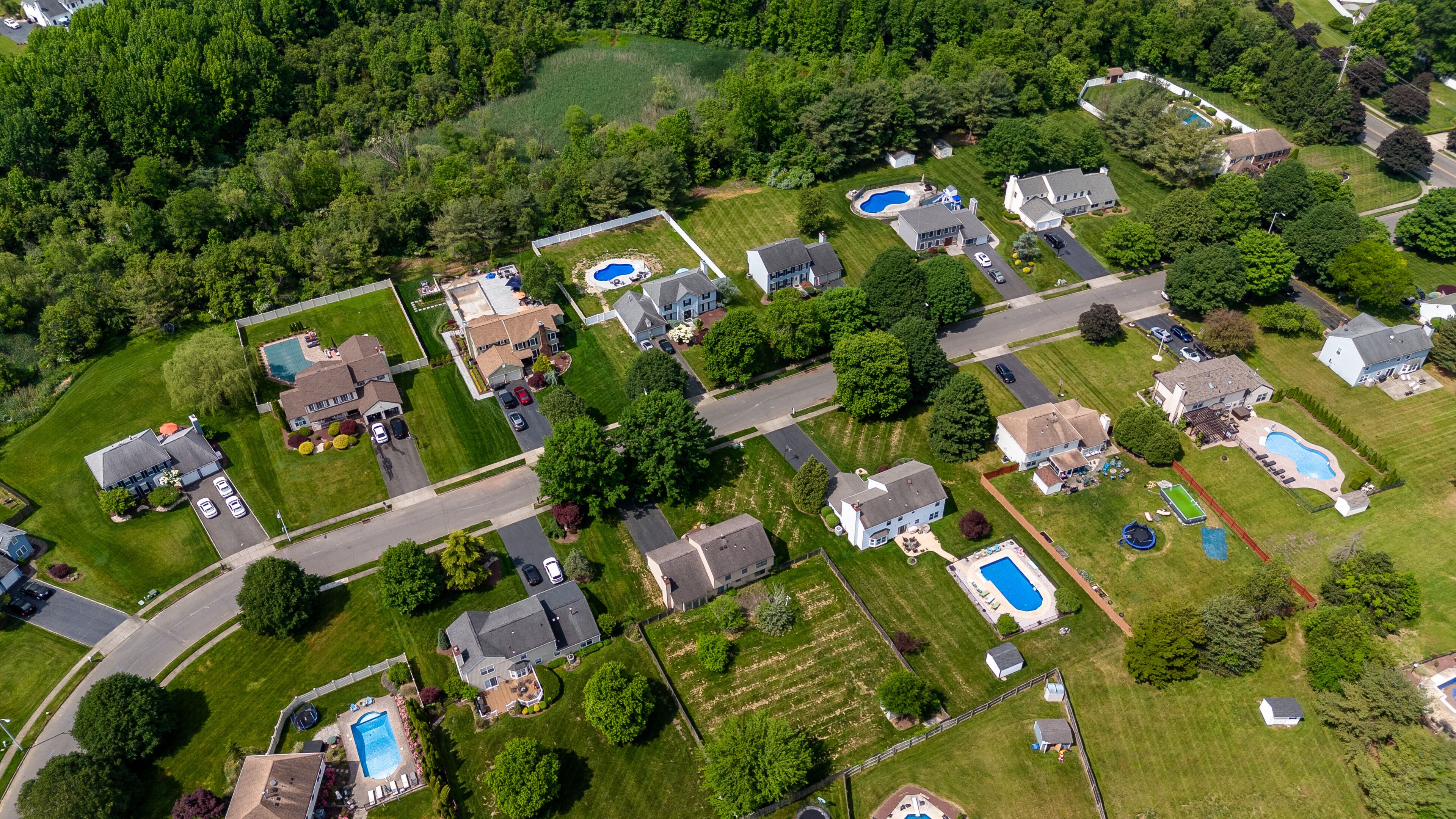A residential area with houses, swimming pools, and a well-maintained lawn.