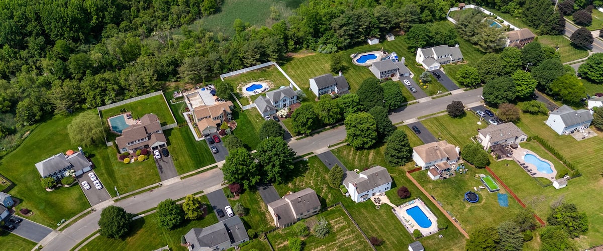A residential area with houses, swimming pools, and a well-maintained lawn.