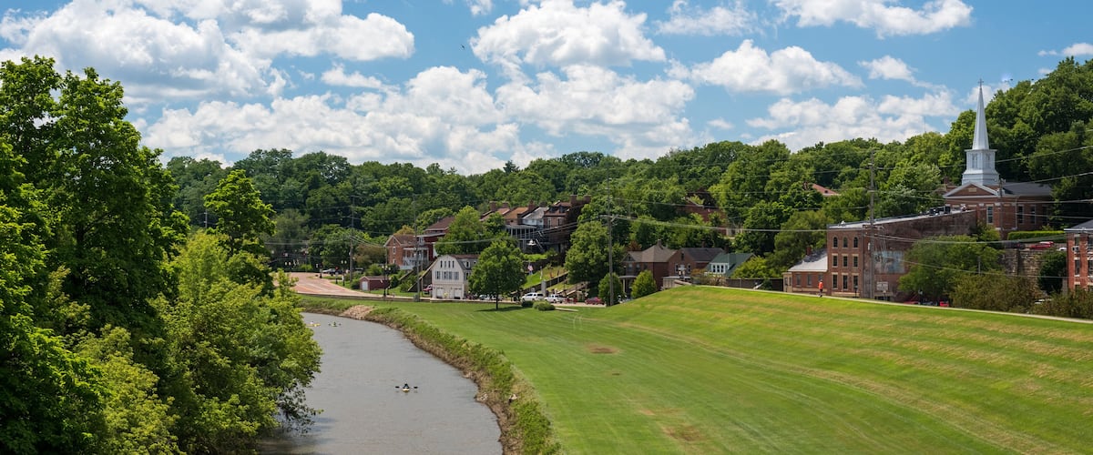 A river, green field, and a church with a steeple.