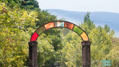 Uma colorida estrutura em arco com uma placa que diz "GOSPEL RUN" e "CONNIE'S SWILL" em um parque.