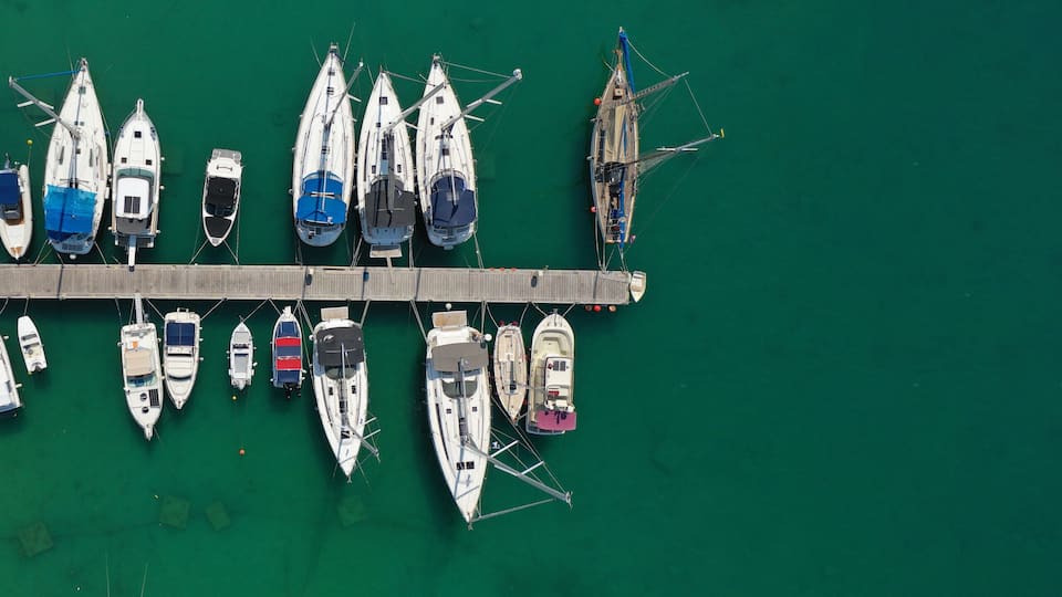 Aerial drone top down ultra wide photo of sail boats anchored in port and Marina of main town of Aegina island, Saronic gulf, Greece