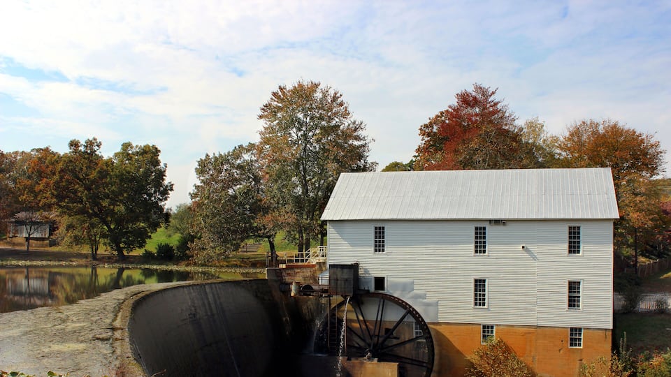 A water mill with a white building and a large water wheel.