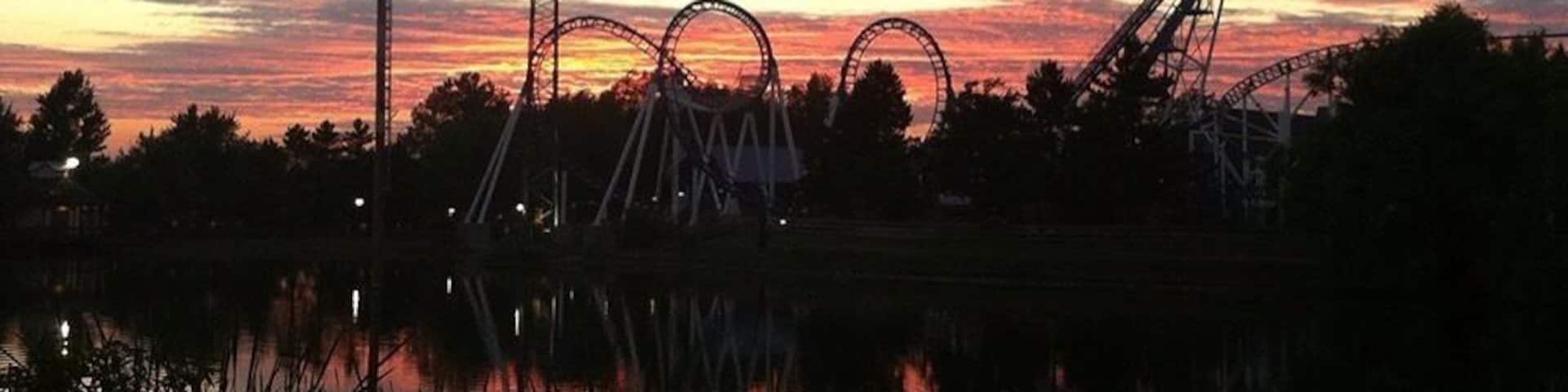 A roller coaster at dusk with a sunset sky.