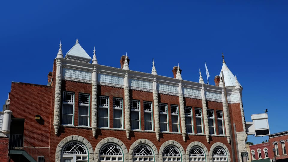 A historic building with a red brick facade, white trim, and multiple arched windows.