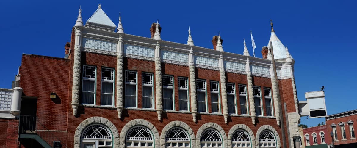 A historic building with a red brick facade, white trim, and multiple arched windows.