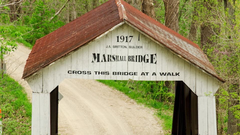 A wooden bridge with a sign reading "1917 J.A. Britton, Builder" and "Cross this bridge at a walk."