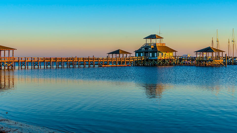 A pier with multiple wooden structures and a boat in the water.