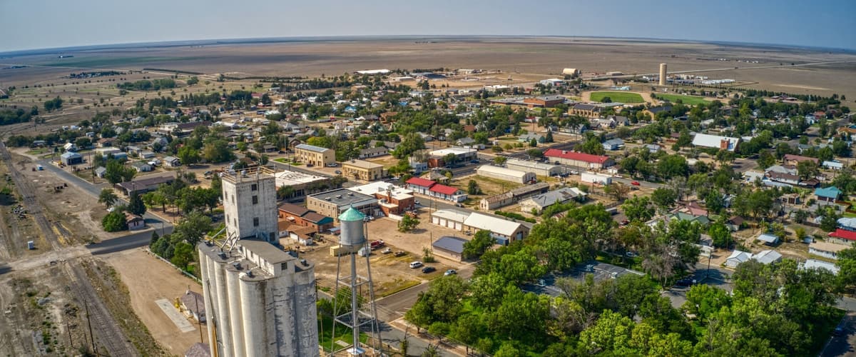 An aerial view of a town with a prominent grain silo, a church, and a water tower.