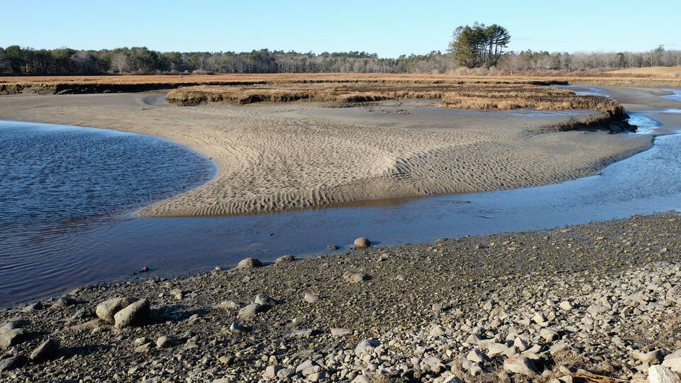 A riverbank with pebbles and a clear sky.