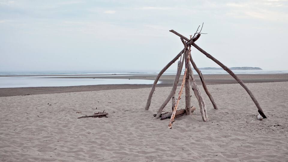 A sandy beach with a wooden structure made of logs.