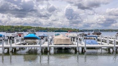 Covered boats and pontoon boats at a pier on a lake with dramatic clouds.