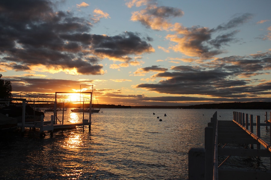 A sunset over a calm body of water with boats docked at a pier.