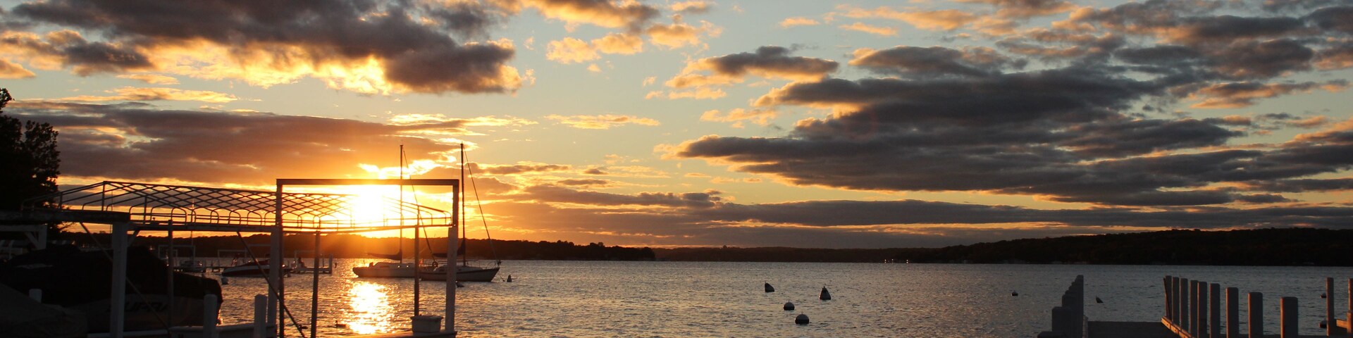 Un atardecer sobre una superficie de agua tranquila con barcos amarrados en un muelle.