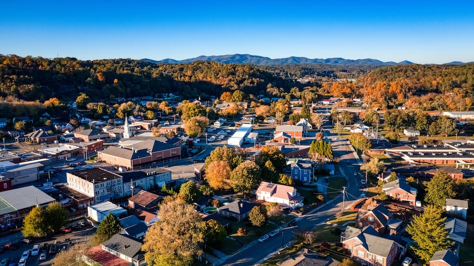 A town with a central church, surrounded by residential houses and a mountainous backdrop.