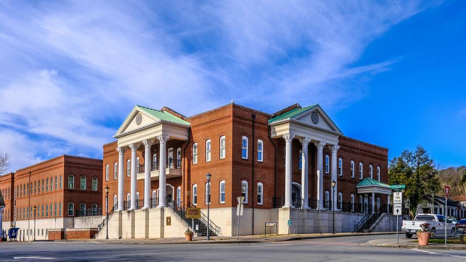 A large brick building with white columns and a green roof.
