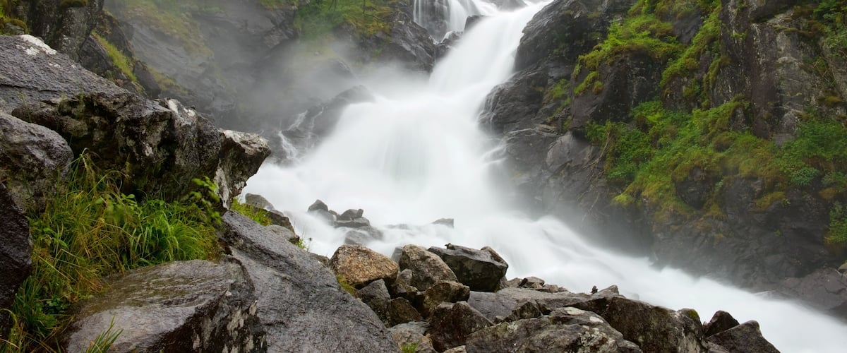 A waterfall cascading through a rocky gorge with lush greenery.