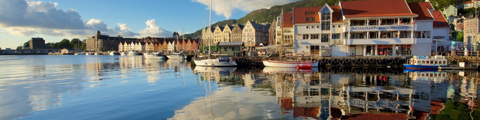 A calm harbor with boats, traditional buildings, and a mountain backdrop.