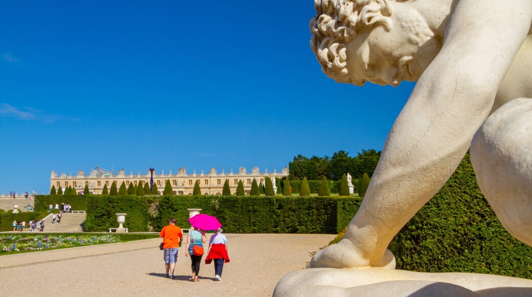 Versailles showing a garden and a statue or sculpture as well as a small group of people