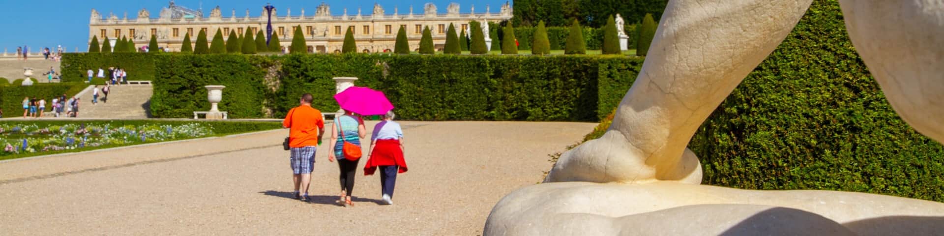 Versailles showing a garden and a statue or sculpture as well as a small group of people