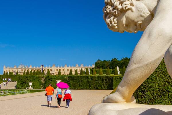 Versailles showing a garden and a statue or sculpture as well as a small group of people