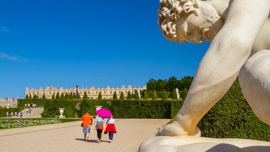 Versailles showing a garden and a statue or sculpture as well as a small group of people