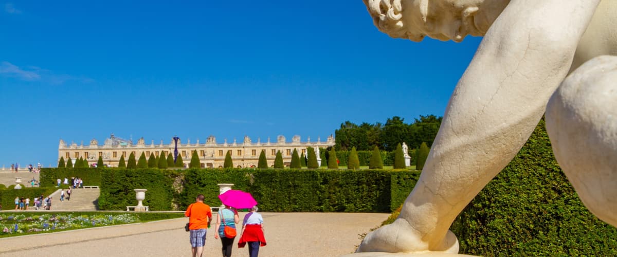 Versailles showing a garden and a statue or sculpture as well as a small group of people