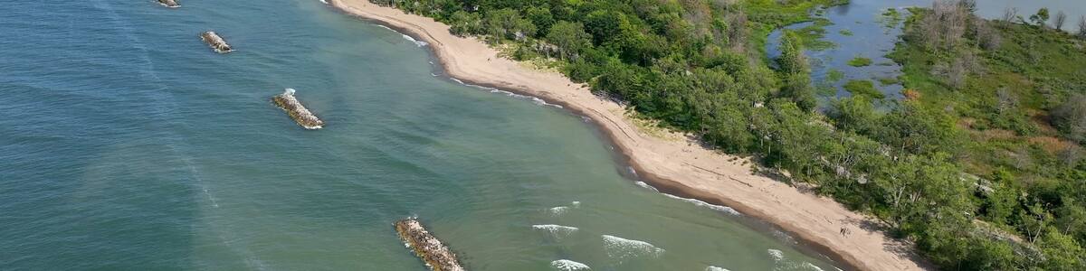 Beautiful sandy beach and coastline of barrier island on Lake Erie Pennsylvania Presque Isle State Park with nature preserve in sunshine on summer day with blue sky and calm waves and surf