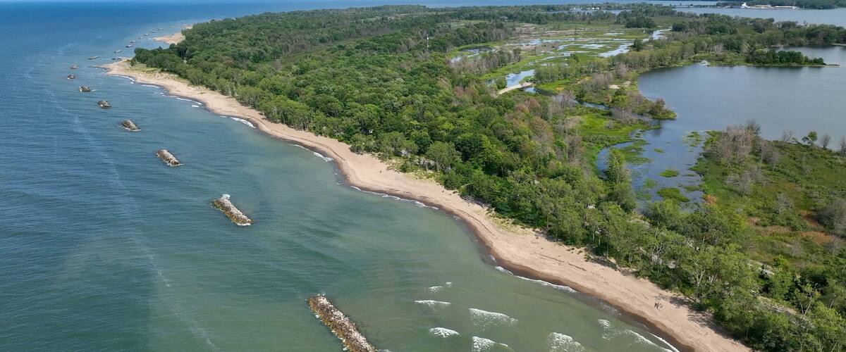 Beautiful sandy beach and coastline of barrier island on Lake Erie Pennsylvania Presque Isle State Park with nature preserve in sunshine on summer day with blue sky and calm waves and surf