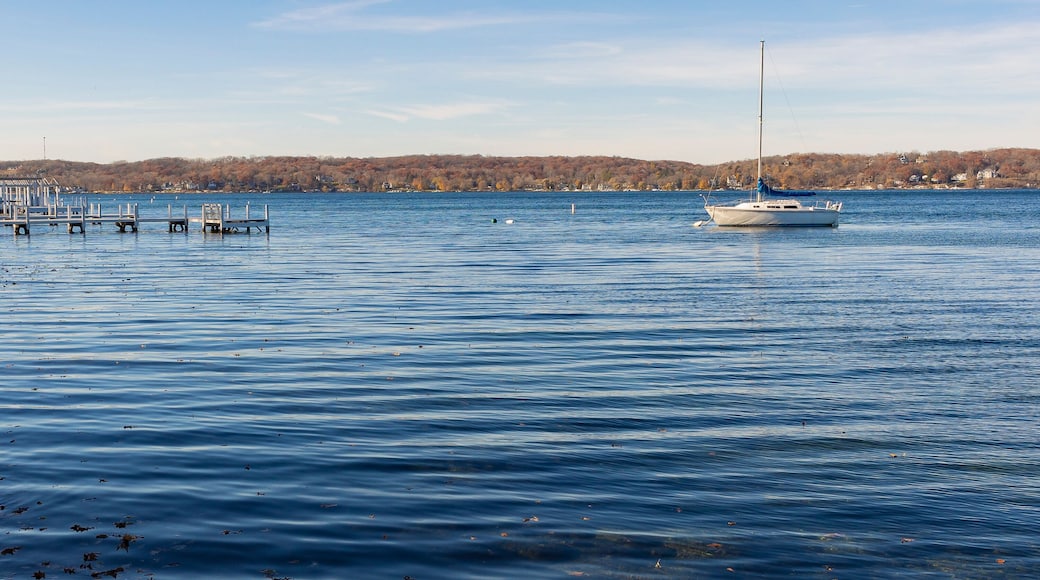 A single sailboat anchored in a lake near a pier on a clear day.