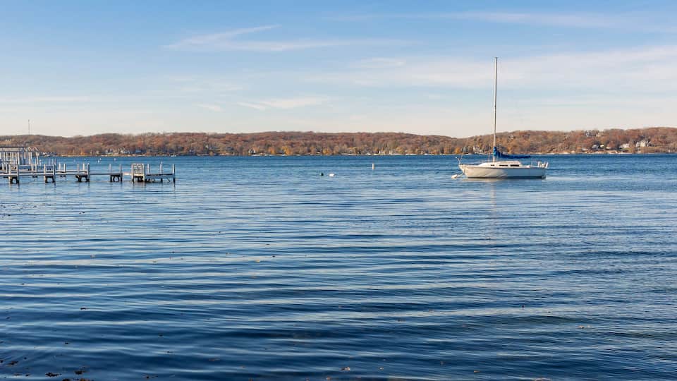A single sailboat anchored in a lake near a pier on a clear day.