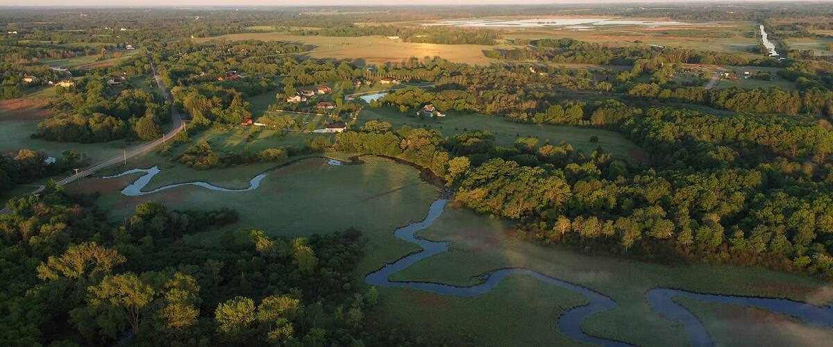 A river winding through a forested landscape with scattered buildings.