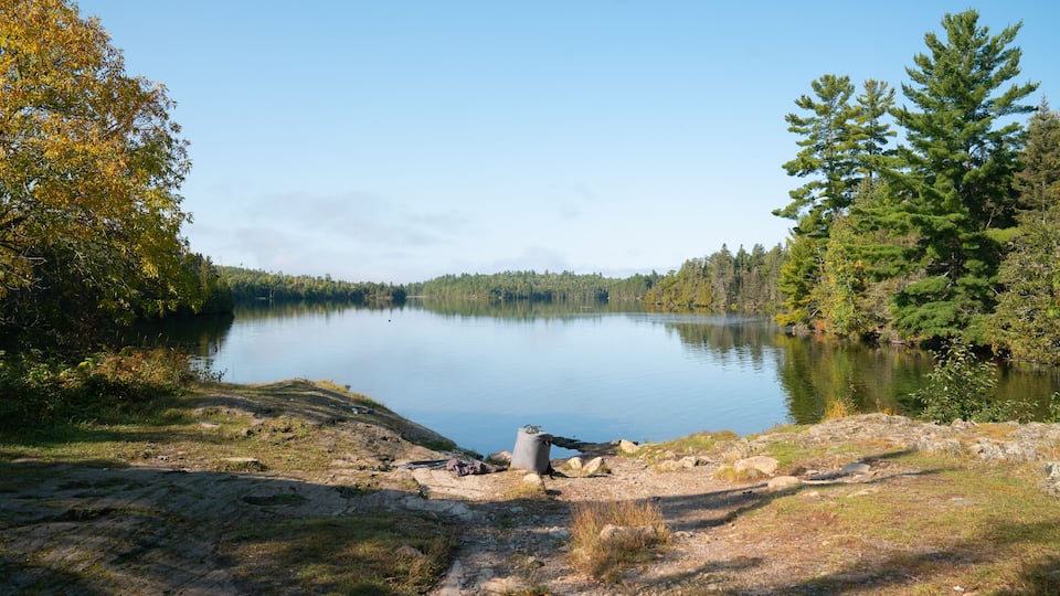 A calm lake surrounded by trees and a rocky shoreline.