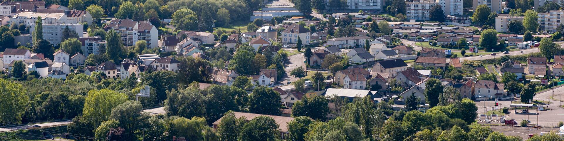 A town nestled in a valley with a prominent church on a hill, surrounded by residential buildings and greenery.