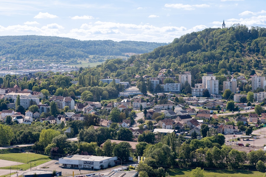 Una cittadina situata in una valle, con una chiesa imponente su una collina, circondata da edifici residenziali e vegetazione.