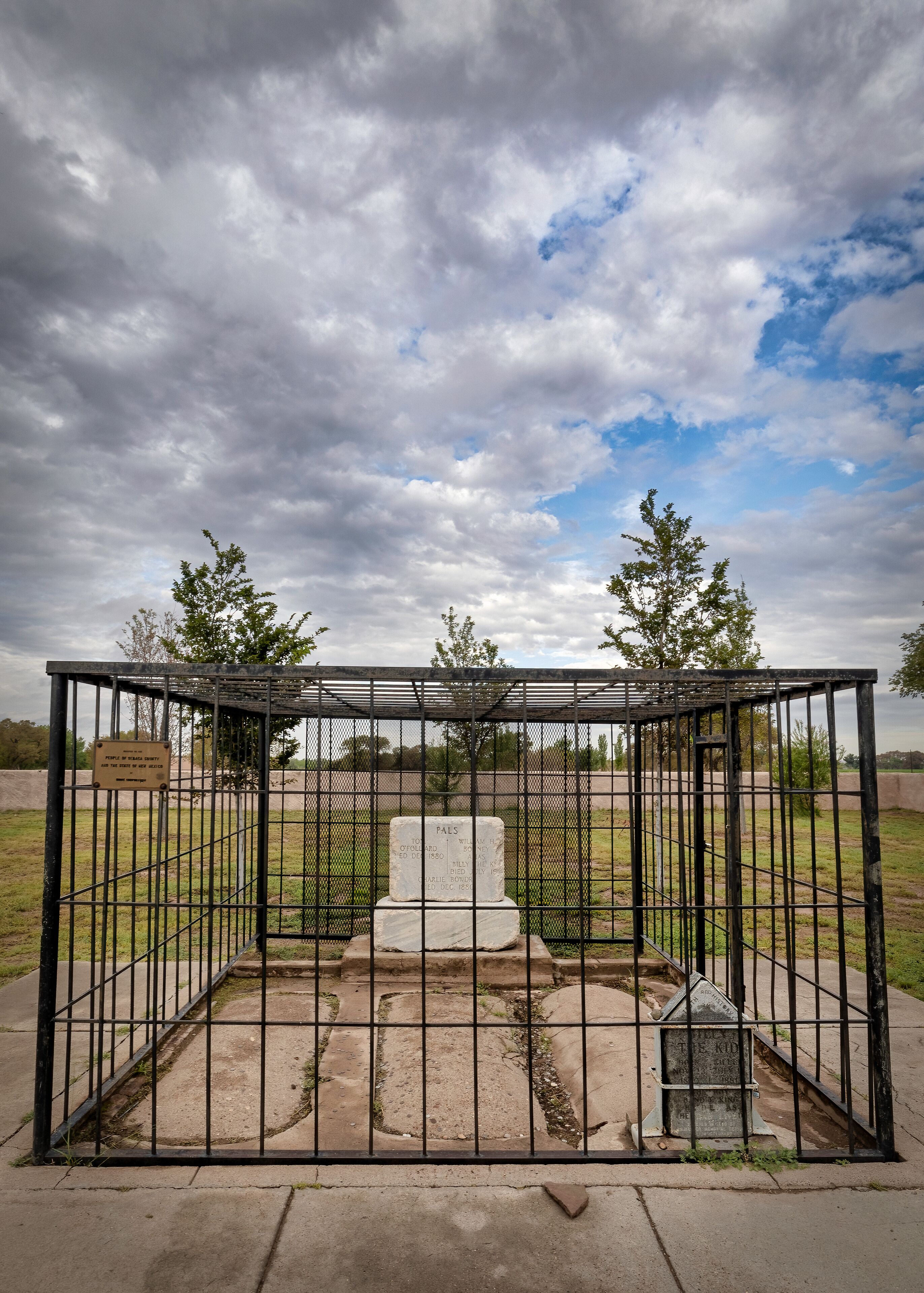A cemetery enclosure with a weathered tombstone and a memorial plaque.