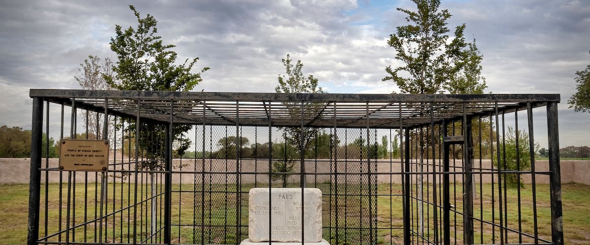 A cemetery enclosure with a weathered tombstone and a memorial plaque.