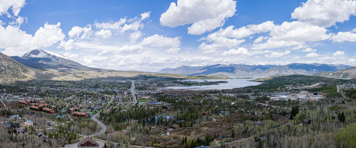 A town nestled in a valley with mountains in the background and a lake in the middle.