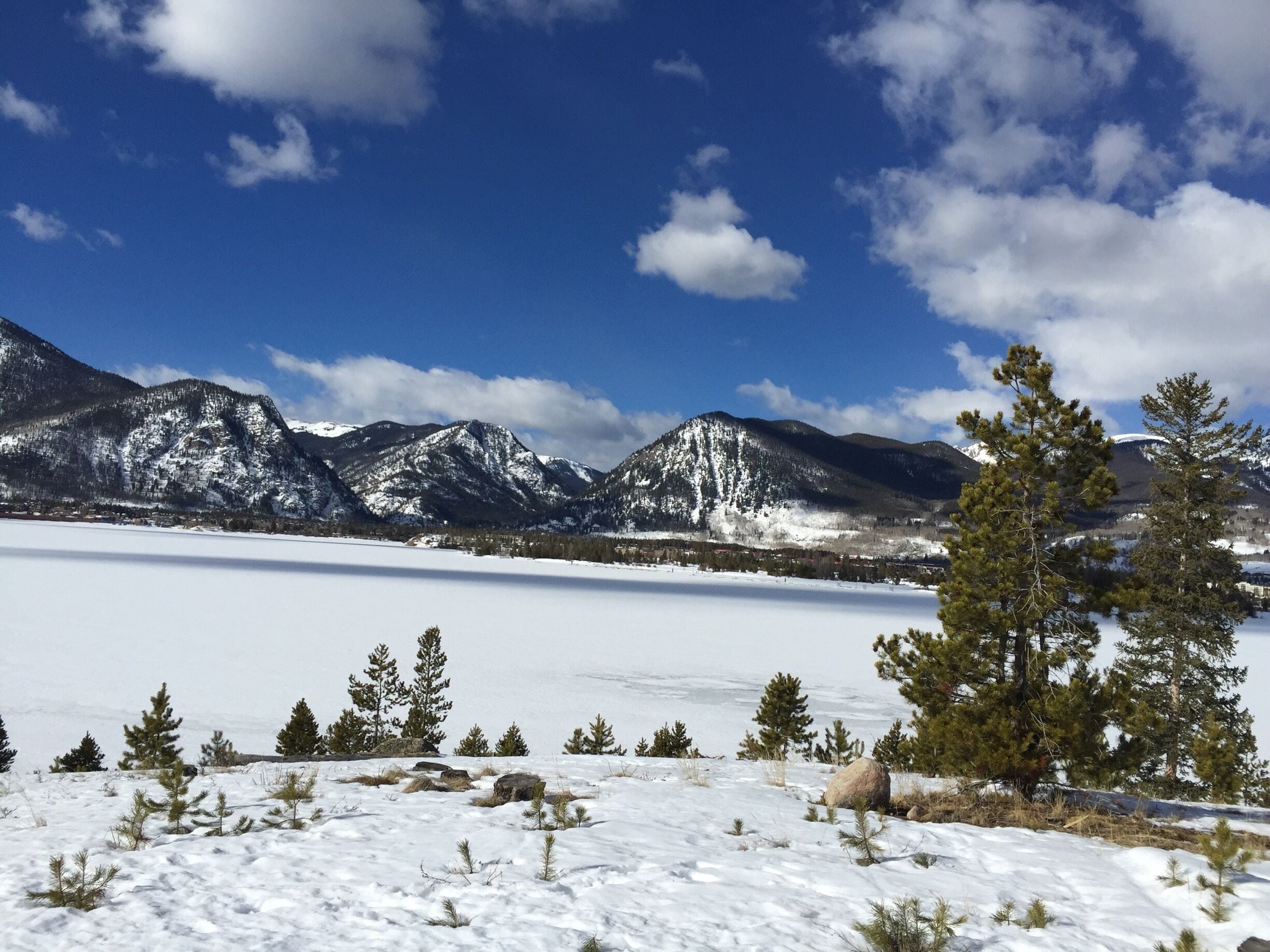A snowy landscape with mountains in the background and a clear blue sky.