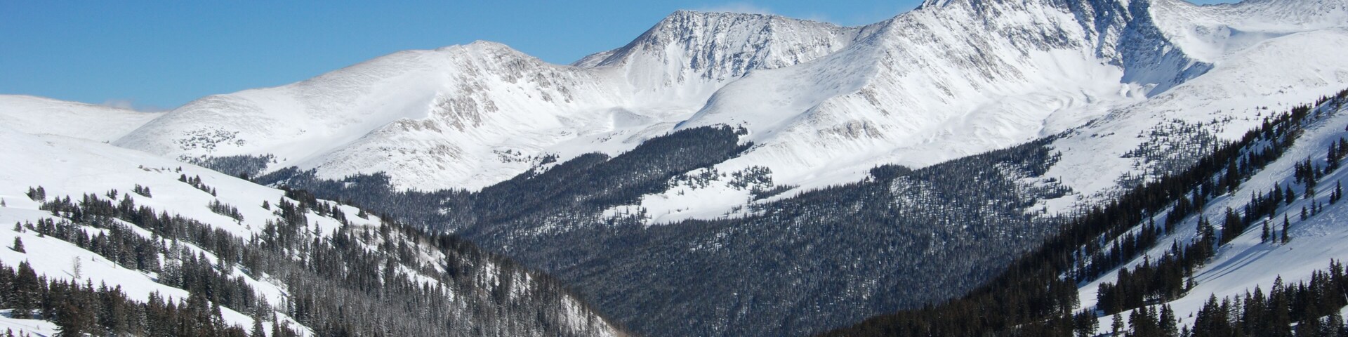 Cordilheira nevada sob céus azuis e límpidos.