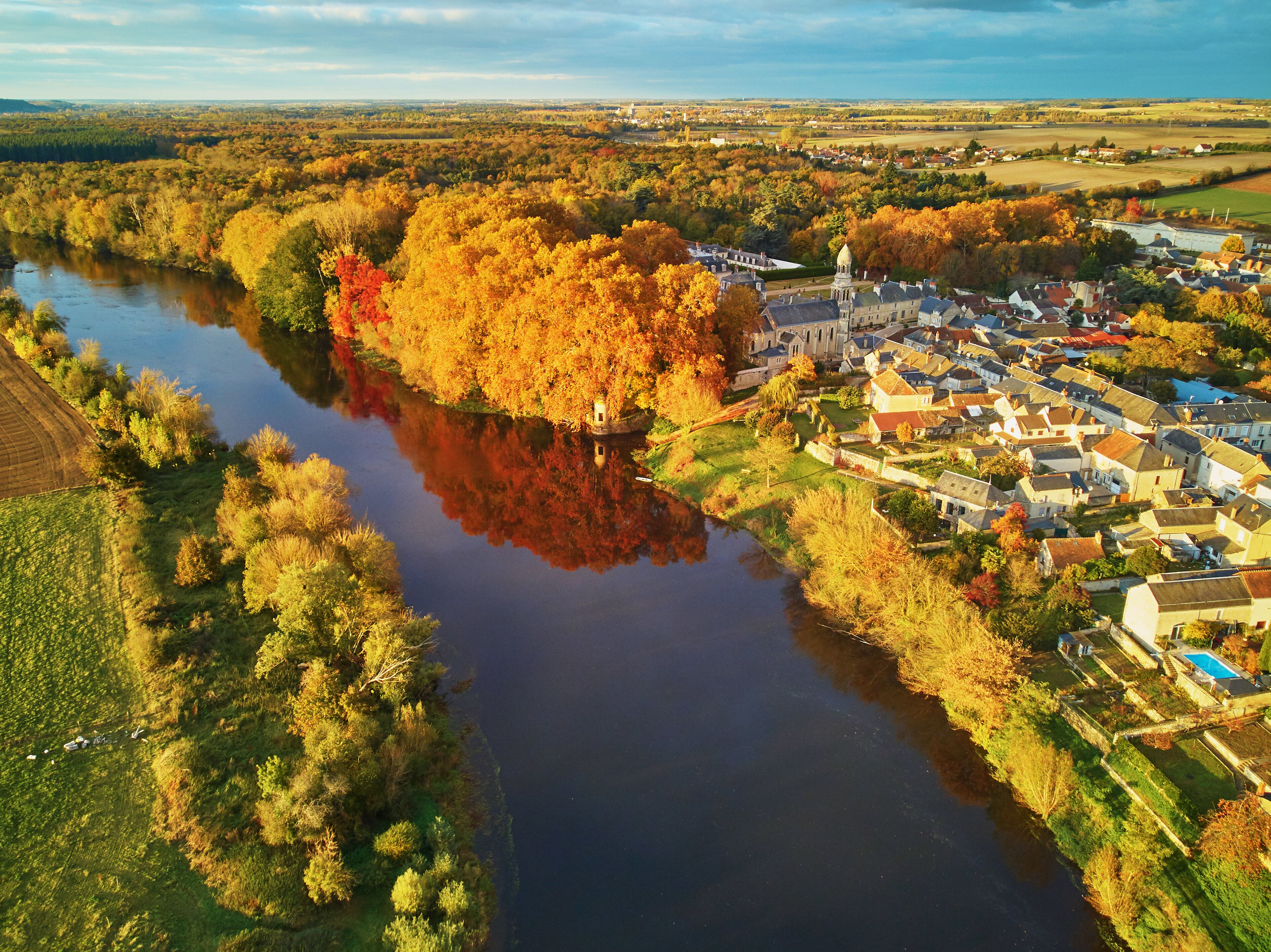Autumn forest and river Vienne near medieval castle of Les Ormes, France