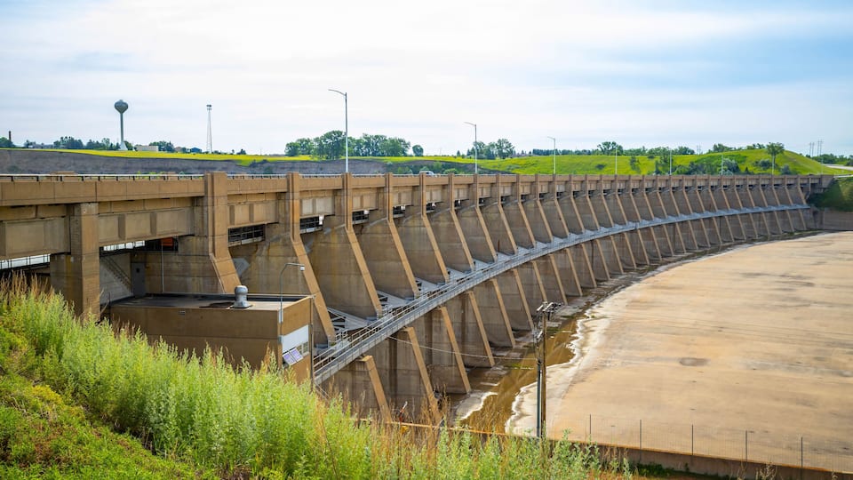 A large dam with a concrete spillway and a bridge over it.