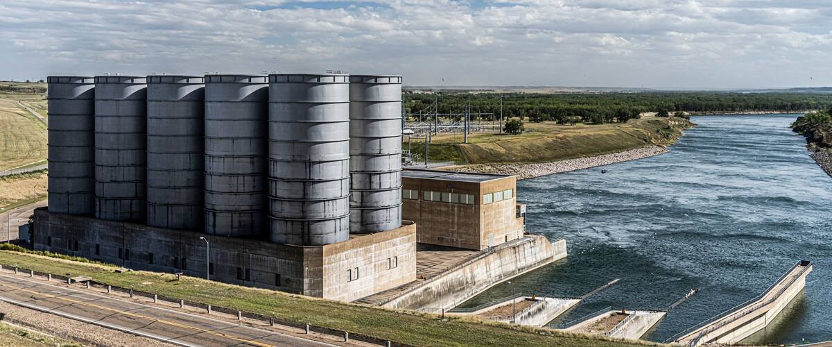 A large industrial facility with multiple silos by a river.