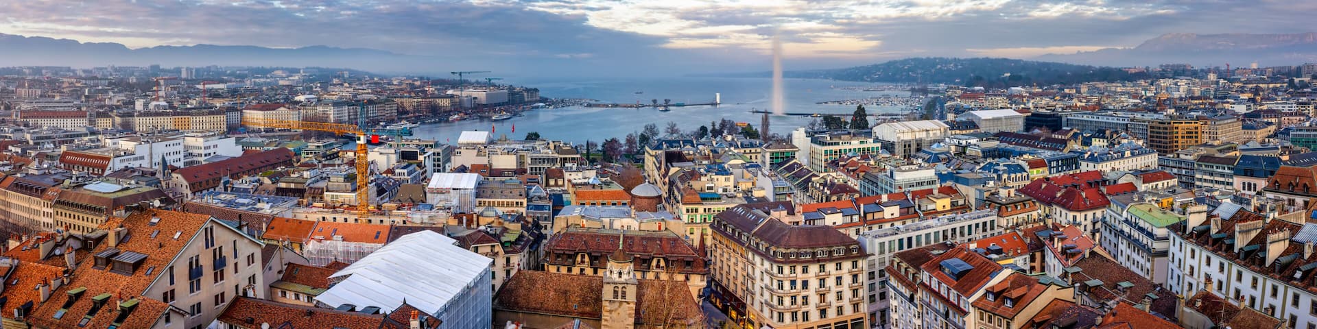 Elevated, panoramic view of the skyline and lake of Geneva, Switzerland, during a winter sunset with fog