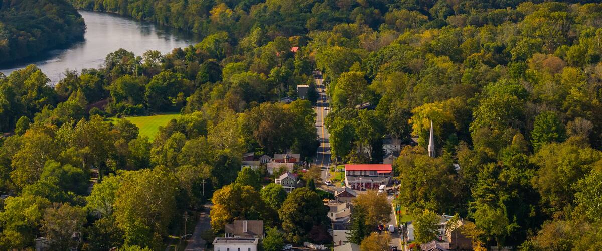 A river winding through a densely wooded area with a small town and a church.