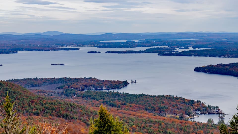 A lake surrounded by forested hills with autumn foliage.
