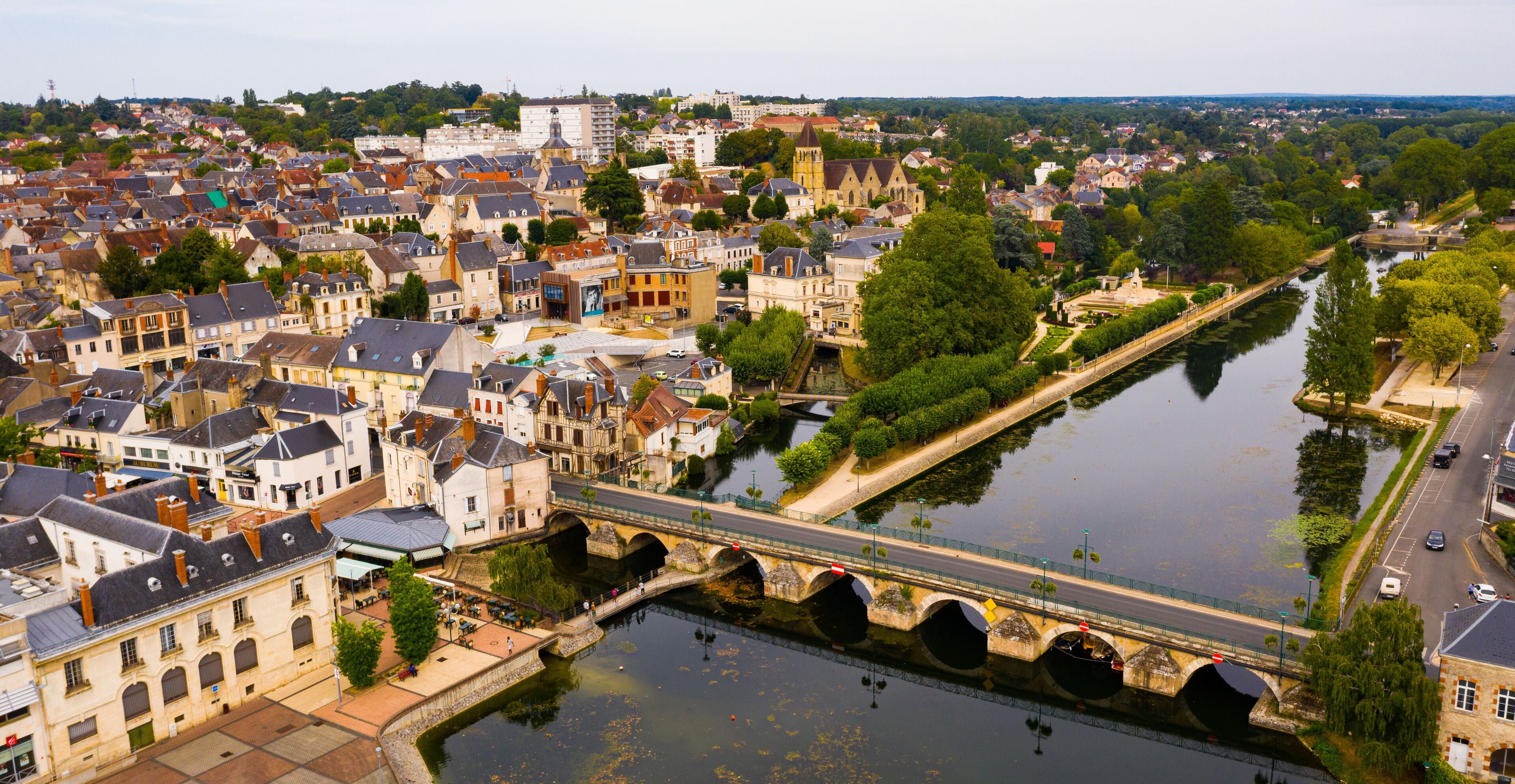 A river with a bridge, historic buildings, and a castle in the background.