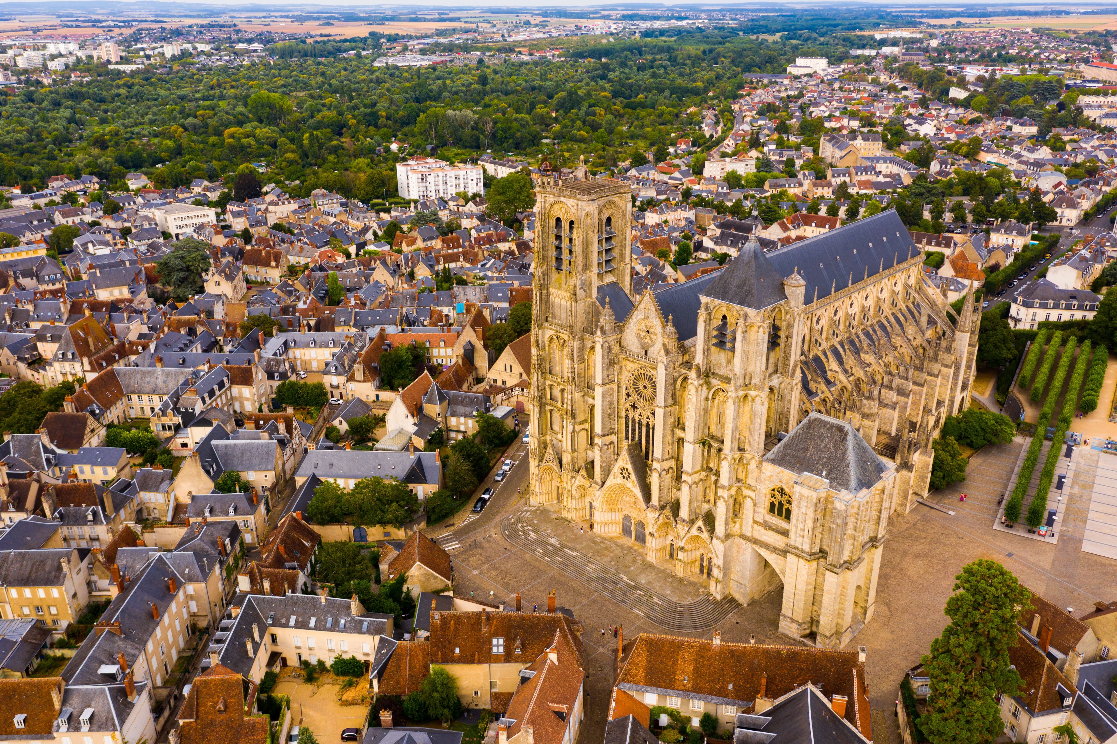 A cathedral with a tall tower, surrounded by a densely packed town with historic buildings.
