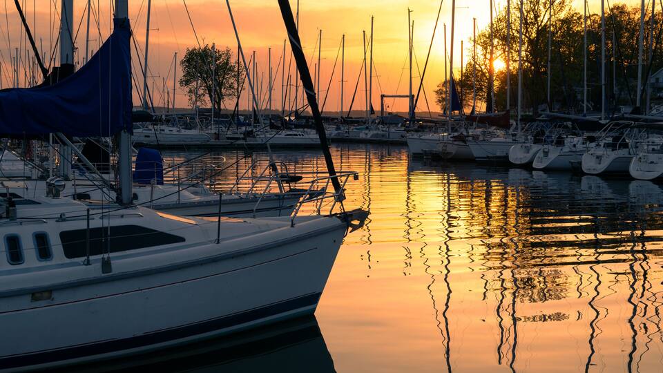 A marina with multiple sailboats docked at sunset.