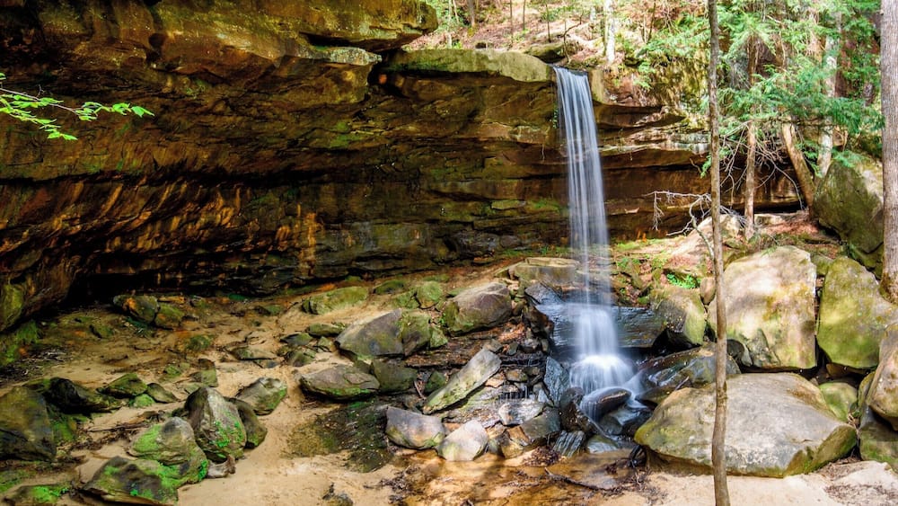 A waterfall cascading over rocks in a forested area.